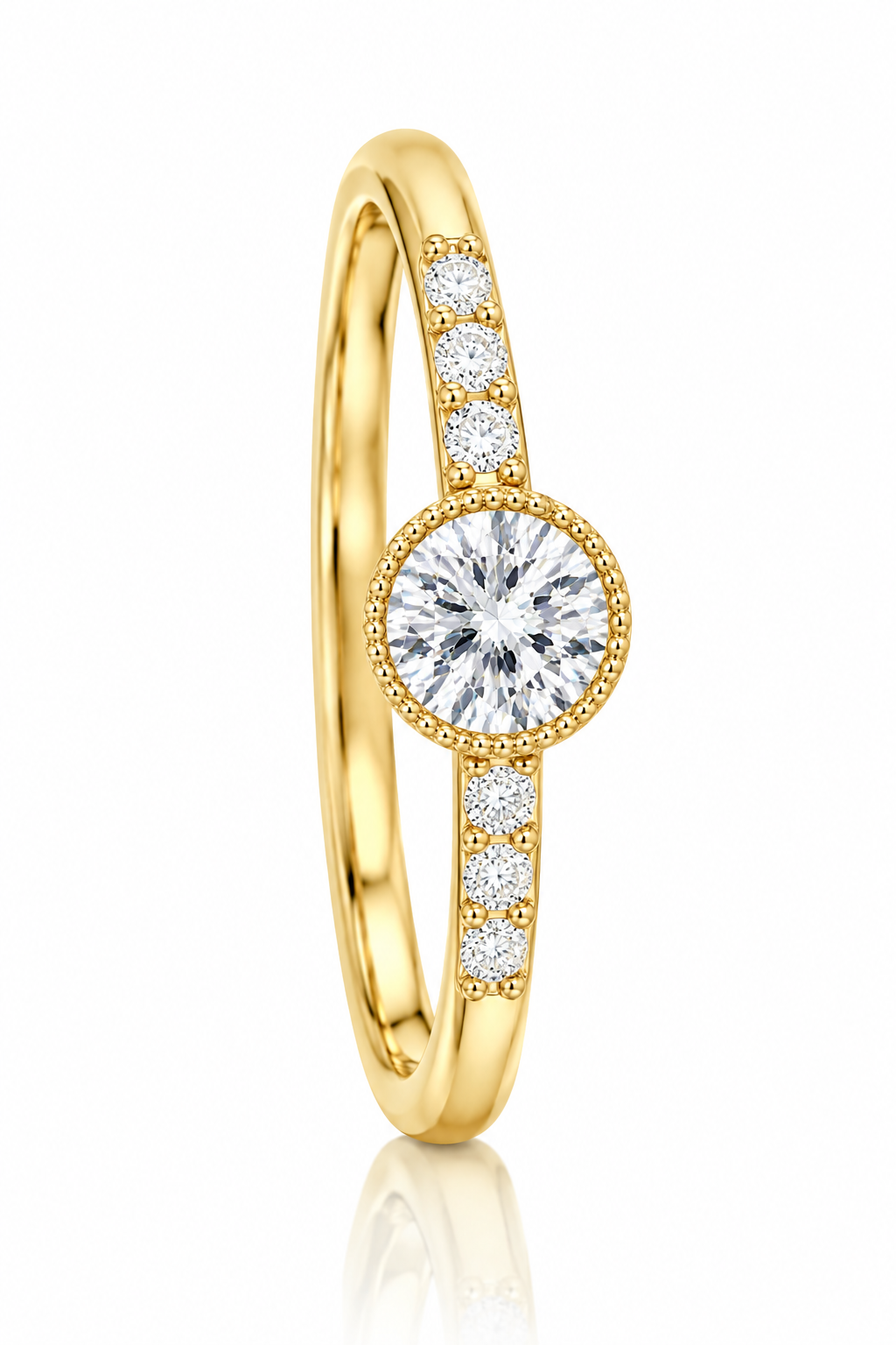 A yellow gold ring featuring a round-cut diamond center stone in a beaded halo, with smaller diamonds set along the band, shown on a clean white background with a soft reflection.