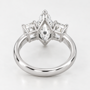 A silver ring featuring a marquise-cut center stone and three baguette-cut side stones, set in a polished silver band on a light gray background.