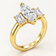 A yellow gold ring featuring a marquise-cut center diamond flanked by two baguette-cut side diamonds, shown on a clean off-white background.